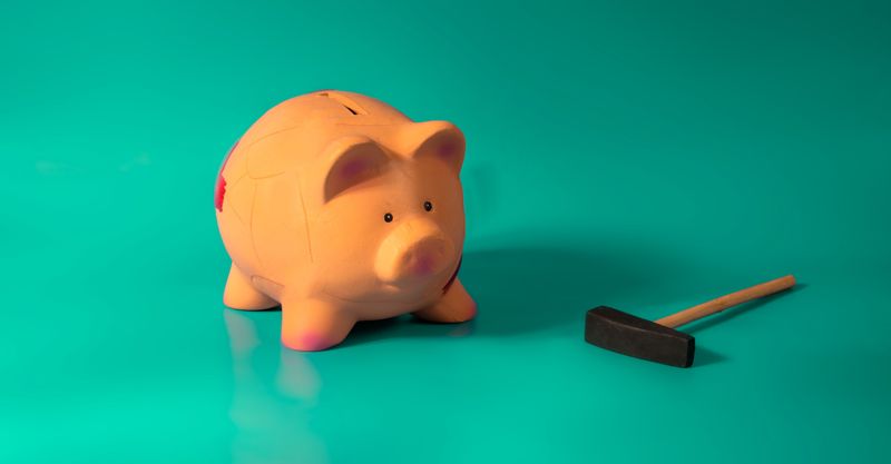 A small piggy bank next to a hammer