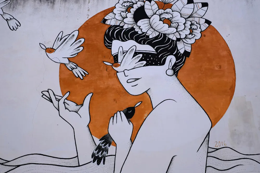 Graffiti on a wall shows a woman letting birds fly