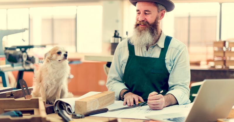 Ein Schreiner an der Werkbank mit Werkzeug und Laptop